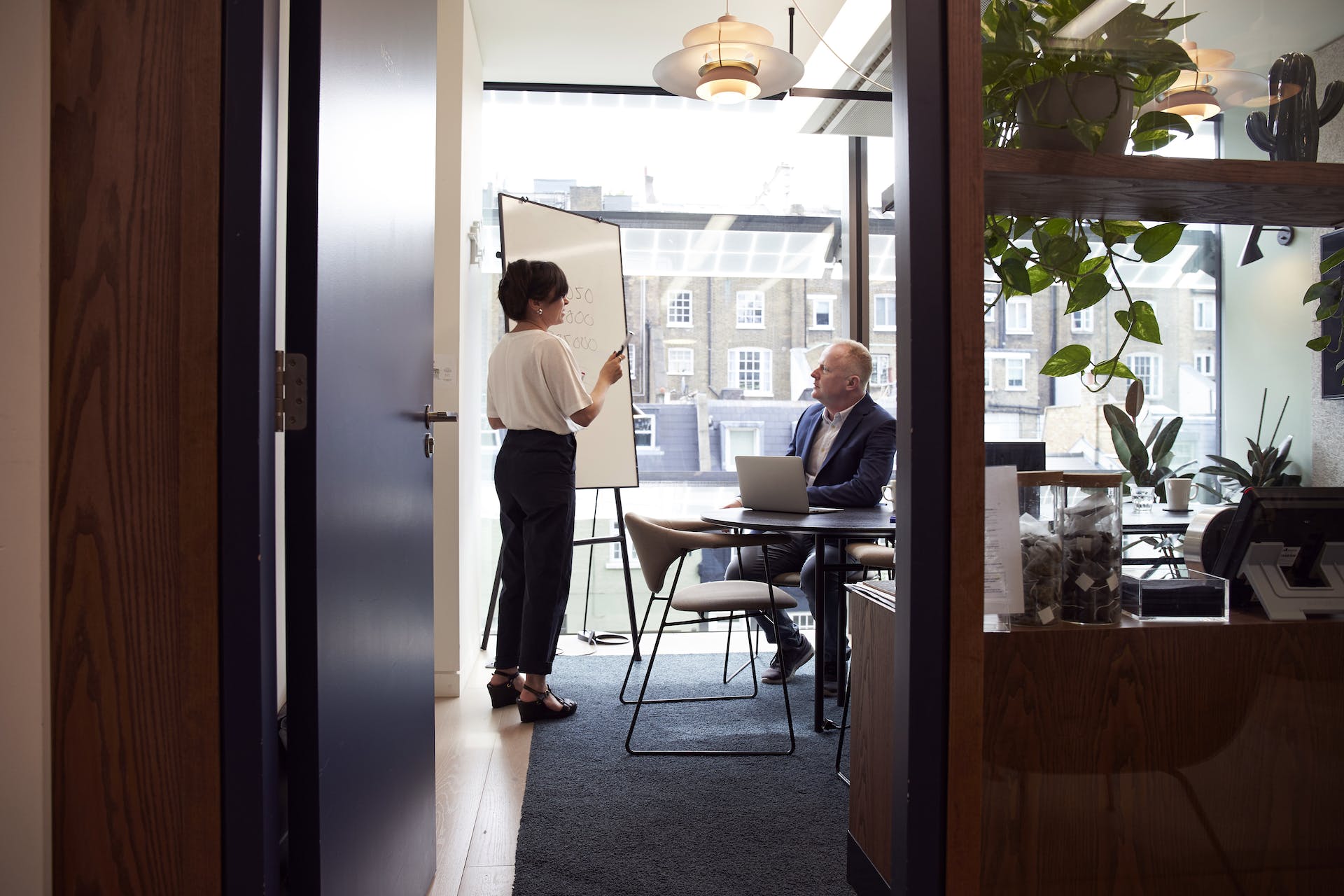 Woman presenting digital marketing services on a whiteboard to a man with a laptop in a modern office in Australia